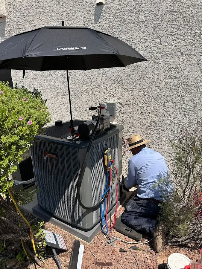 HVAC technician performing outdoor AC maintenance in Gonzales